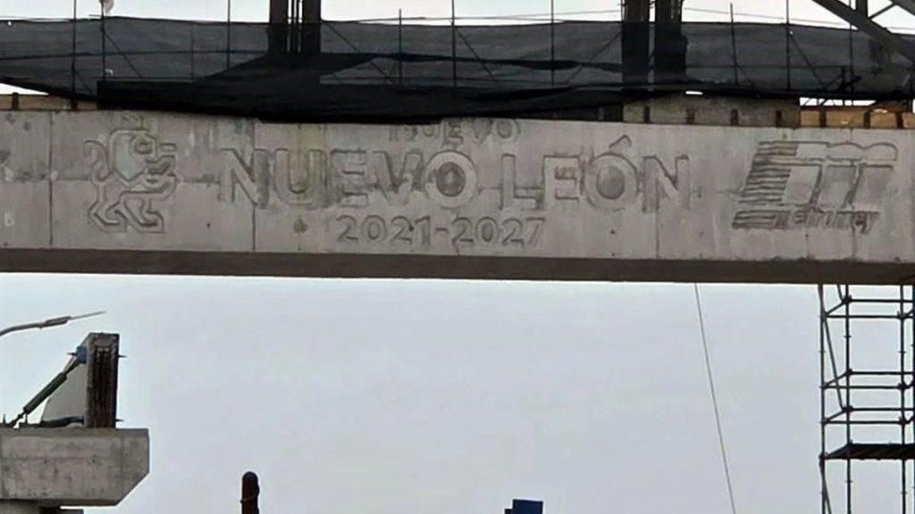Obra-fantasma-de-la-linea-6 1 - La Razón Nl Concrete Beam at a Construction Site Bearing the Inscription 'nuevo Leon 2021-2027' with Logos on Both Ends and Scaffolding in the Background. - La Razón Nl