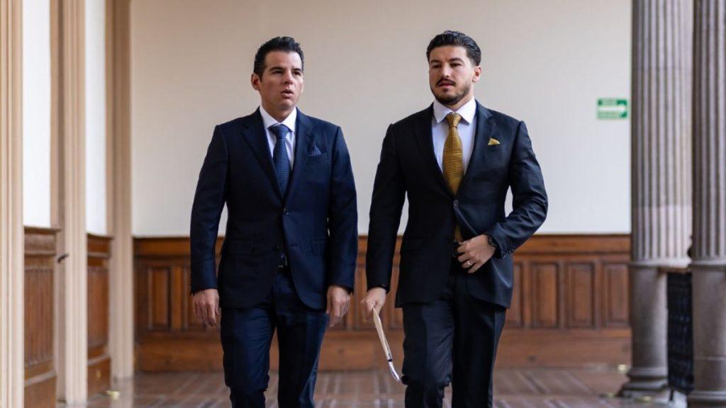 Two Well-dressed Men in Dark Suits Walk Down a Wood-paneled Hallway, One Holding a Folder or Document. - La Razón Nl