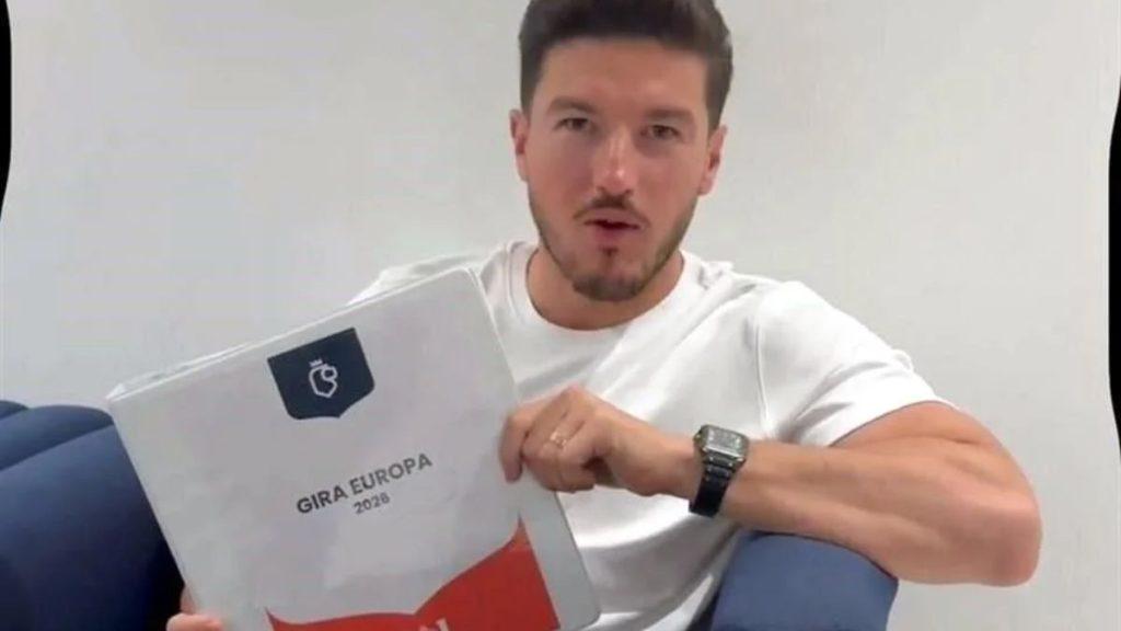Viajes-de-samuel-garcia - La Razón Nl Man in a White T‑shirt Sits on a Blue Couch, Holding a Folder That Reads 'gira Europa 2026' with a Black Logo. - La Razón Nl
