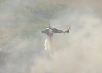 Firefighting Helicopter Releasing a Water Drop Amid Thick Smoke over a Hillslope. - La Razón Nl