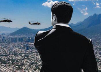 Back View of a Man in a Suit Overlooking a Sprawling City with Two Helicopters Hovering in the Sky Behind Him. - La Razón Nl