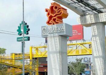 Orange Abstract Lion Sculpture Atop a Concrete Column with a 'nueva' Sign and a Yellow Pedestrian Overpass Nearby in an Urban Street Scene. - La Razón Nl
