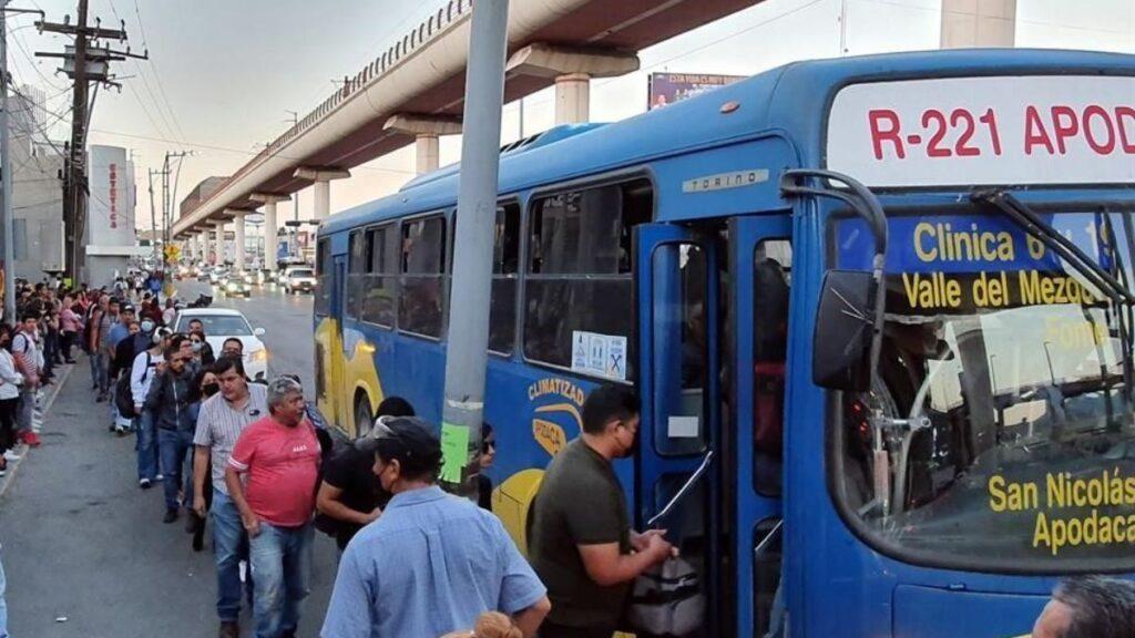 Blue City Bus with Passengers Queuing to Board Along a Curb Under an Elevated Rail Structure at a Busy Street Edge. - La Razón Nl