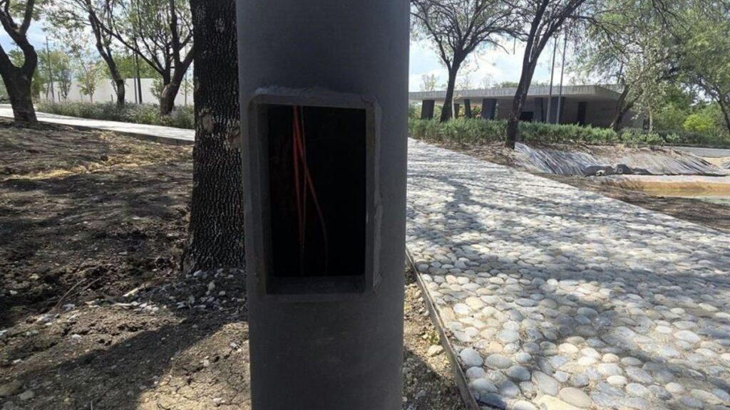 Open Electrical Junction Box on a Concrete Post with Red Wires Visible Inside, Outdoors in a Park Setting. - La Razón Nl