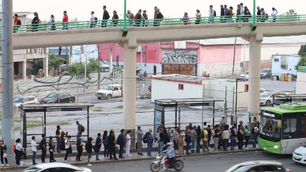 People Line Up at a Bus Stop Under a Pedestrian Overpass, a Green City Bus Parked Nearby. - La Razón Nl